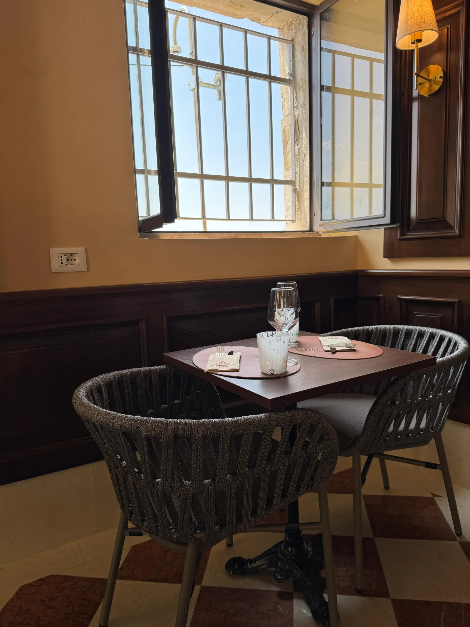 Set table beside a Venetian grated window in the San Basilio dining room