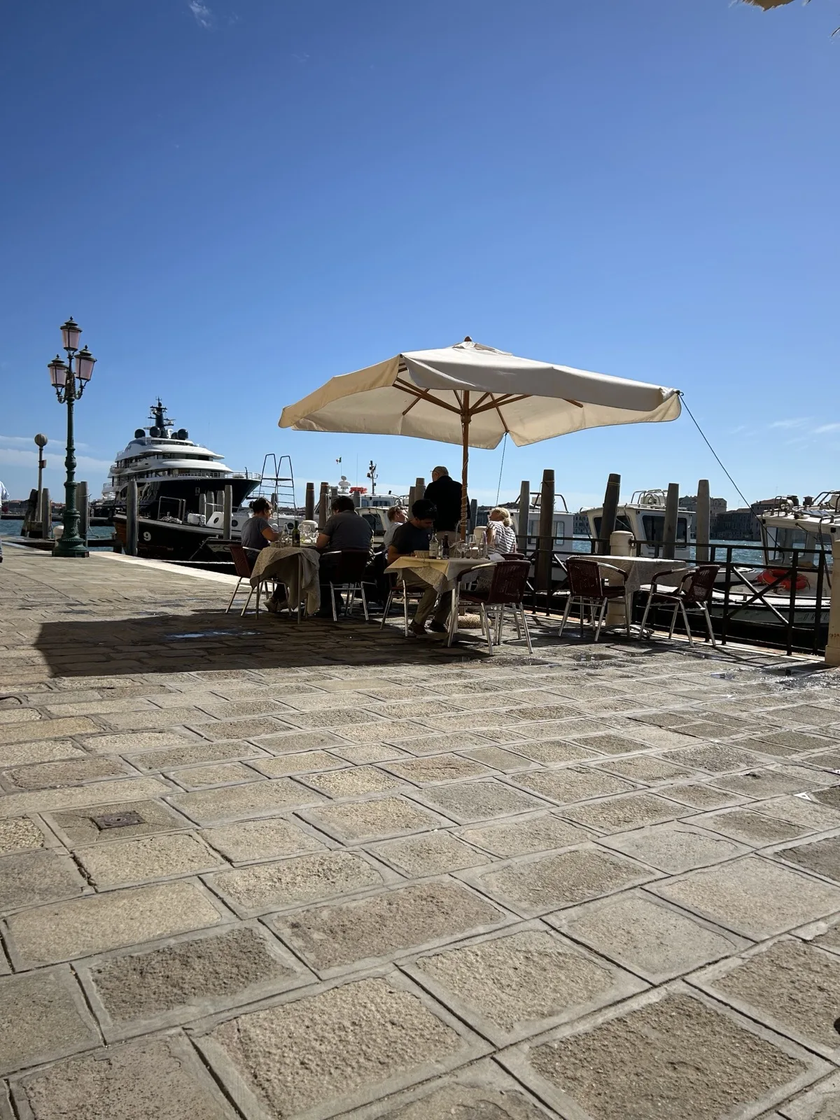 Outdoor tables with a parasol on the San Basilio waterfront in Dorsoduro, Venice, overlooking the water