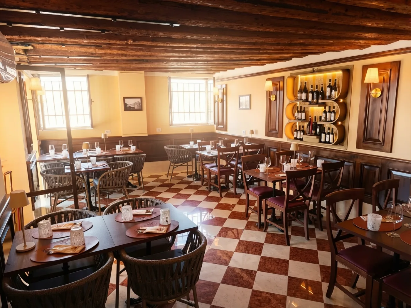 Trattoria San Basilio dining room with exposed beams, burgundy checkerboard floor, wine display and windows onto the Dorsoduro canal