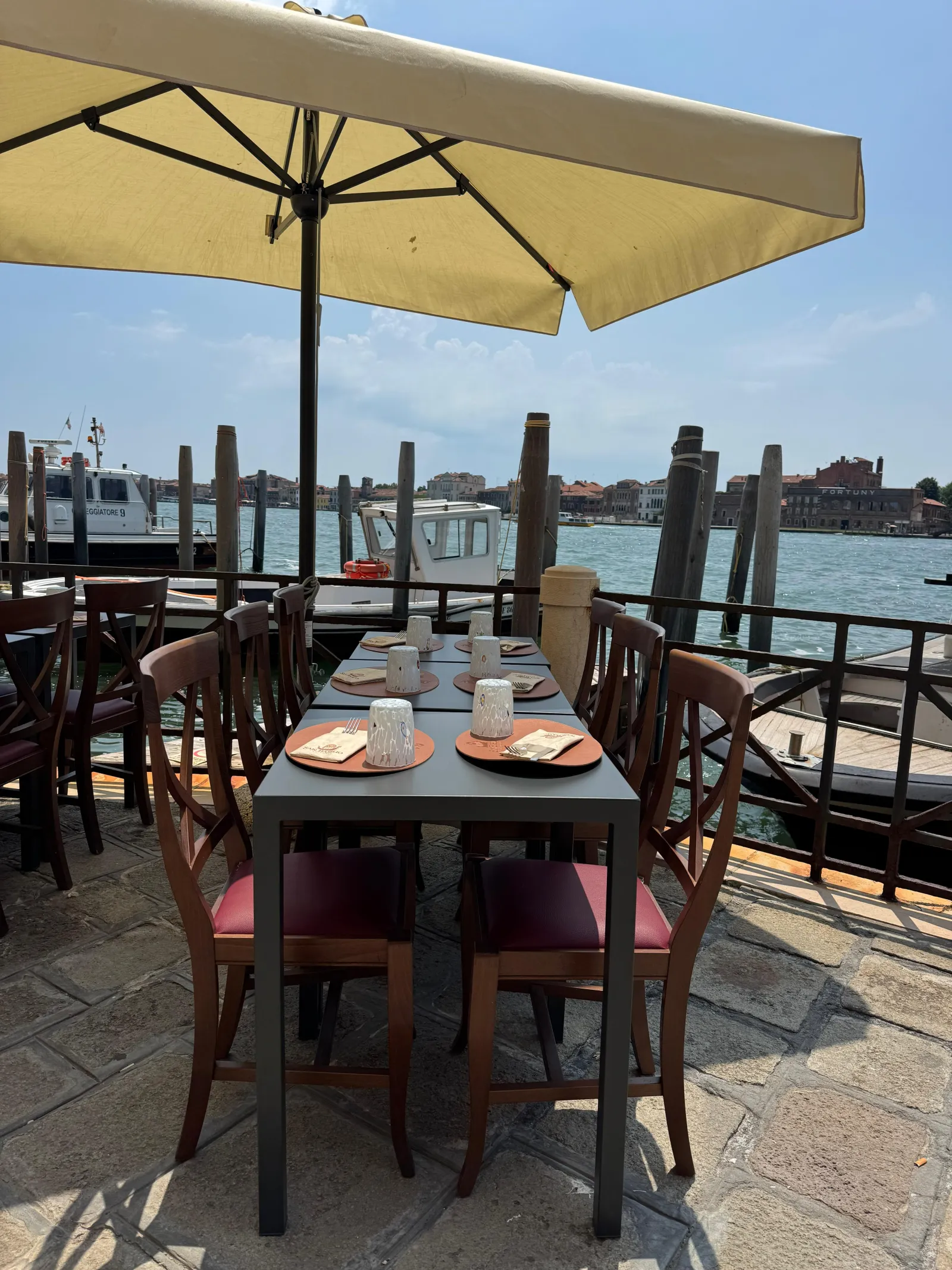Warm interior with laid tables and a Venetian view hanging on the wall