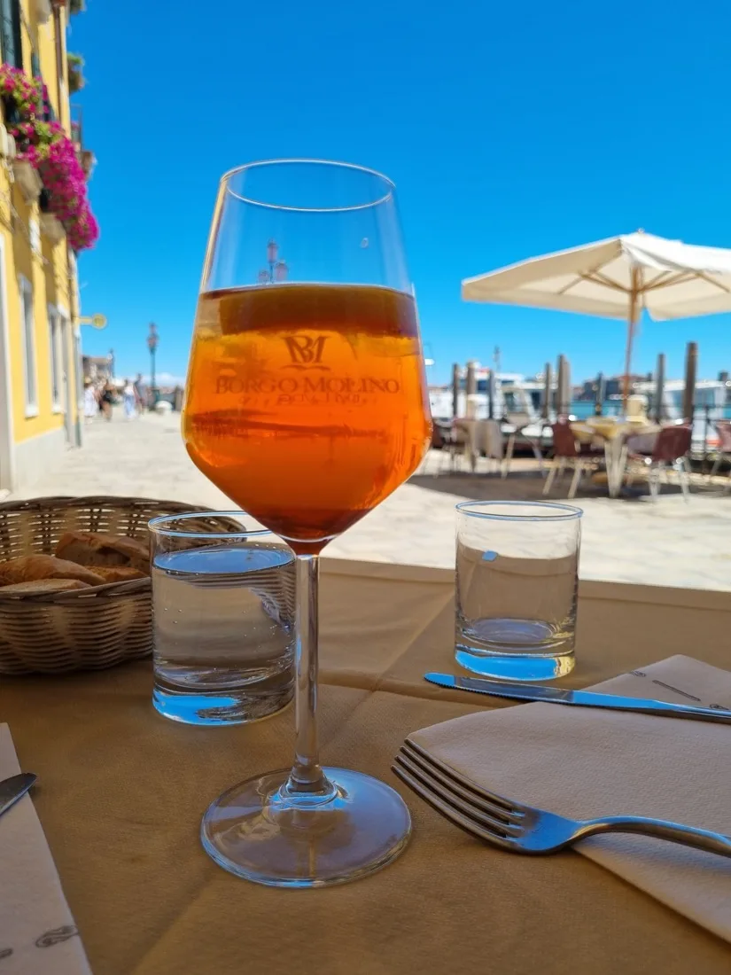 Venetian spritz served at the table with a view of the lagoon and parasols